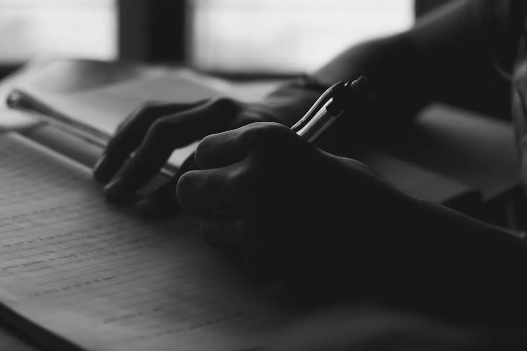 Iemand schrijft met een pen in een notitieboek.