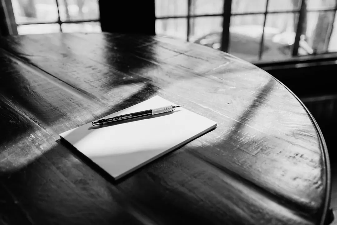 Een pen ligt op papier op een houten tafel.